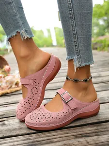Detailed close-up of pink hollow-out wedge sandals with buckle strap and floral patterns.