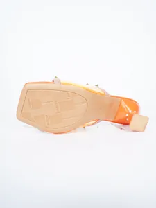 Nahaufnahme der rutschfesten Gummisohle von orangefarbenen High-Heel-Sandalen mit Nieten