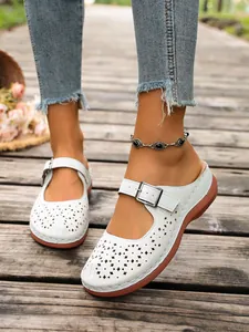 White hollow-out clog sandals with buckle strap on wooden walkway for summer outdoor wear