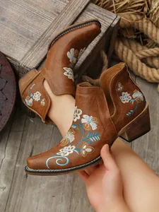 Vista detallada de botines marrón retro con bordado floral intrincado y tacón grueso.