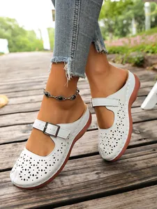 Detailed view of white hollow-out wedge clogs featuring an adjustable metal buckle strap