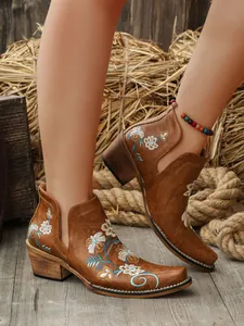 Primer plano de botines marrones vintage con bordados florales y tacón grueso cómodo