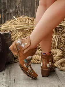 Primer plano detallado de botas western vintage marrones con bordado floral y tacón grueso.