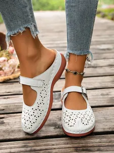 Detail view of white hollow-out wedge slippers with adjustable buckle strap for summer