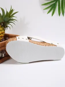 Close-up showing the white ribbed sole and cork texture of a wedge platform sandal with rivets
