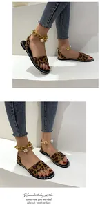 Detail of leopard print flat sandals with gold chain and pearl ankle strap