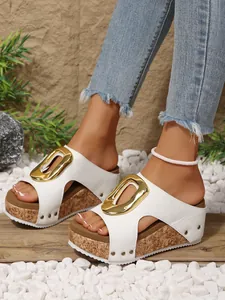 Close-up of white platform wedge sandals featuring a gold buckle and stylish rivet accents.