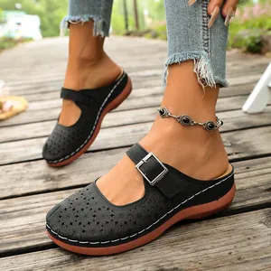 Detail of black cutout wedge mules with floral pattern and adjustable buckle strap