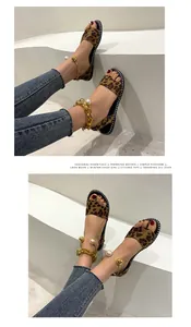 Detailed view of leopard print flat sandals featuring gold chain and pearl anklet accents.
