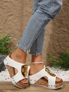Close-up of white wedge platform sandals with gold buckle and rivet details