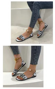 Detail view of zebra print flat sandals with elegant pearl and gold anklet strap
