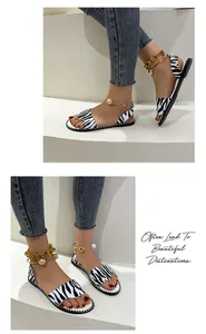 Close-up of zebra print flat sandals with pearl and chain ankle straps.