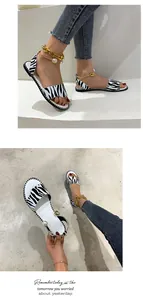 Close-up of zebra print flat sandals featuring stylish pearl and gold chain ankle straps