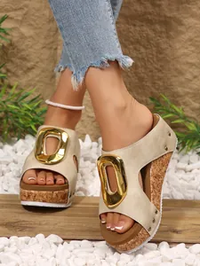 Close-up view of beige platform wedge sandals with a gold buckle and cork texture sole