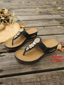 Detail showing black wedge flip-flops with gold metallic discs and a 5.7cm heel height.