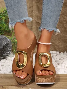 Close-up of brown wedge platform sandals featuring a large gold buckle and cork sole