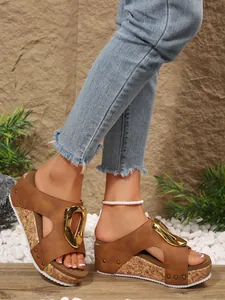 Detailed close-up view of stylish brown wedge sandals with gold buckle and rivet accents