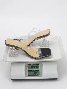 Detailed view of square toe clear high heel sandals with sculptural wine glass heel