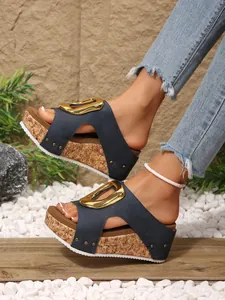 Close-up of navy blue wedge slide sandals with large gold buckle and cork platform sole
