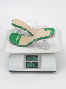 Detailed view of green square-toe sandals with clear heels on a digital scale.