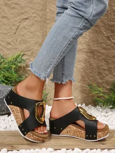 Close-up of black platform wedge sandals with gold buckle and rivet detailing