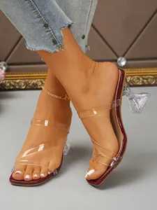 Close-up of square toe high-heeled sandals with transparent straps and wine glass heel.