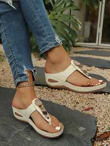 Close-up of stylish wedge thong sandals with metallic sequin details on model's feet