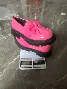 Detailansicht der stylischen rosa Plateau-Loafer mit Schleife auf einer Digitalwaage