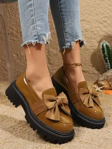 Detailansicht brauner Lack-Loafer mit großer Schleife und dicker schwarzer Plateausohle