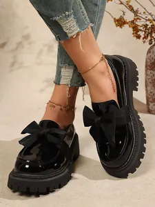 Detailansicht stilvoller schwarzer Lackleder-Plateau-Loafer mit großer Schleife.