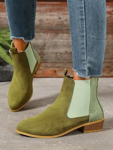 Close-up of olive green vintage Chelsea boots with square heel and textured details.