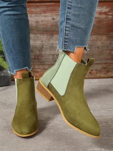 Detailed close-up of olive green suede Chelsea boots with square heel and crocodile pattern