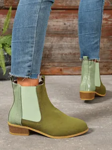 Stylish olive green Chelsea boots with crocodile texture and block heel worn by model.