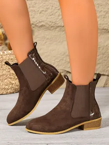 Detailed side view of brown suede Chelsea boots featuring embossed crocodile texture back