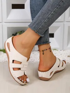 Vue latérale détaillée des mules compensées blanches ajourées portées avec un jean