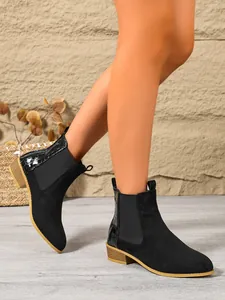 Detail view of women's black suede Chelsea boots with crocodile texture and block heel.