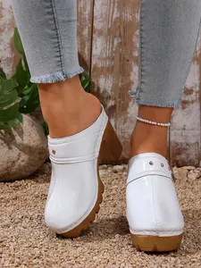 Detail shot of white high-heel platform mules with rivet and buckle accents.