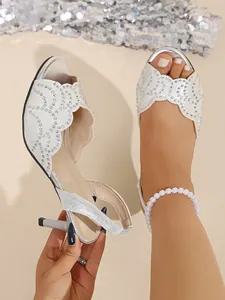 Detailansicht der silbernen Sandalen mit Strasssteinen, dünnem Absatz und Wellenkanten-Design