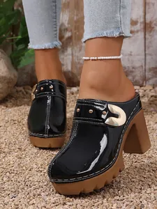 Detailed view of black patent leather mules with thick brown platform and gold rivet accents