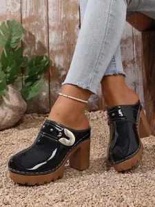 Side view of stylish black patent leather platform clogs with rivet details on feet