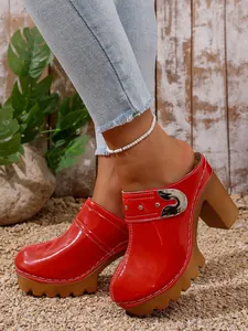 Close-up of stylish red patent leather platform mules with rivet and buckle details