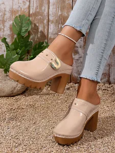 Detailed view of beige patent leather platform mules featuring stylish metal studs and heel