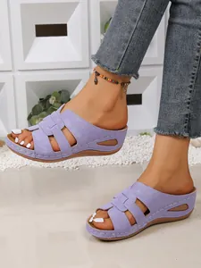 Détail de sandales compensées violettes ajourées avec coutures blanches et bout ouvert