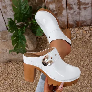 Detail view of white platform clogs featuring gold rivets and thick block heel