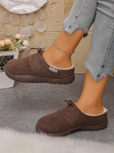 Detailed side view of stylish brown suede slip-on mules with cozy faux fur lining