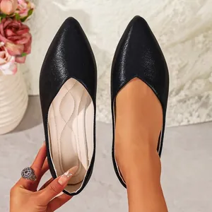 Close-up of black pointed-toe flat shoes with shimmering texture and quilted insole.