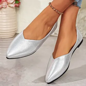 Detailed view of silver pointy-toe flat shoes with a metallic finish on a model.