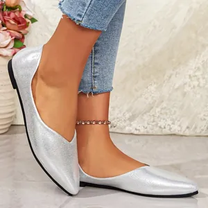 Macro view of elegant silver pointed-toe flats on model's feet in a stylish setting.
