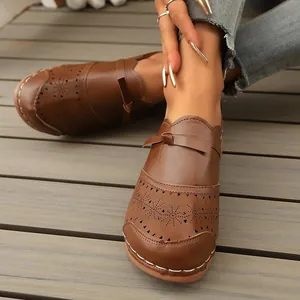 Detailed view of brown retro faux-leather loafers with hollow-out star patterns