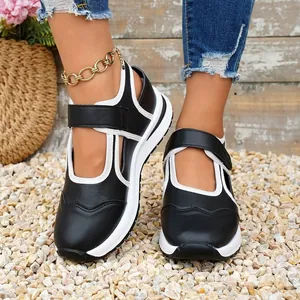 Primo piano di scarpe Mary Jane bianche e nere con suole spesse su ciottoli levigati.